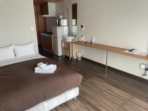 um quarto de hotel com uma cama e uma cozinha em HOTEL Progress inn 名護 MATABee em Nago