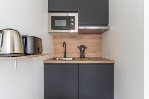 une cuisine avec un évier et un micro-ondes dans l'établissement Magnifique Studio neuf, à Paris