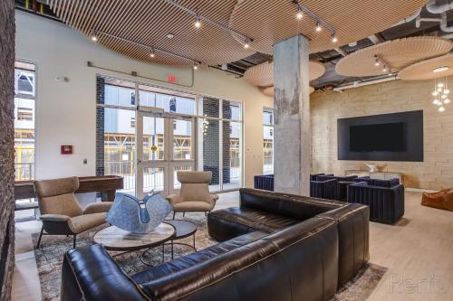 eine Lobby mit einem Ledersofa und Stühlen sowie einem Flachbild-TV in der Unterkunft Premium Spacious Apartments at Paperbox Lofts in Salt Lake City in Salt Lake City