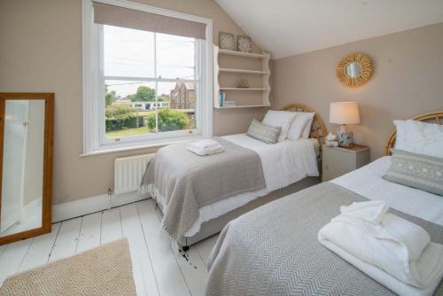 a bedroom with two beds and a window at Fern Cottage in Bembridge