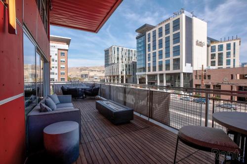 einen Balkon mit einem Sofa sowie Tischen und Gebäuden in der Unterkunft Premium Spacious Apartments at Paperbox Lofts in Salt Lake City in Salt Lake City