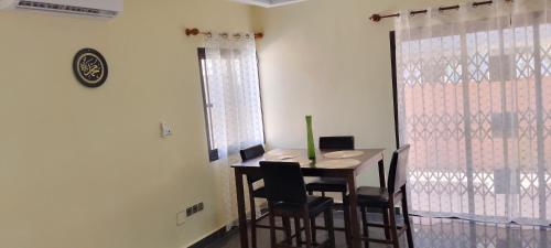 a dining room with a table and chairs and a clock at ADISSA in Cotonou