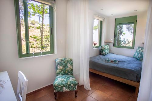 um quarto com uma cama, uma cadeira e 2 janelas em Villa Myrtalia em Mikra Anogia