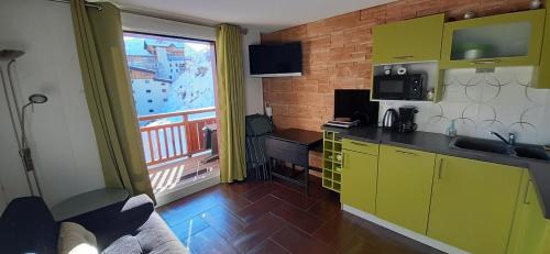 Cette chambre dispose d'une cuisine avec des placards jaunes et d'un balcon. dans l'établissement Charmant Studio 4 pers plein centre Parking privé, à Les Deux Alpes