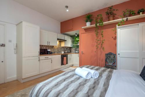 a kitchen with white cabinets and a bed in a room at Amazing Finsbury Park Studio in London