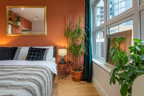 Amazing Finsbury Park Studio في لندن: غرفة نوم بالنباتات وسرير بمرآة