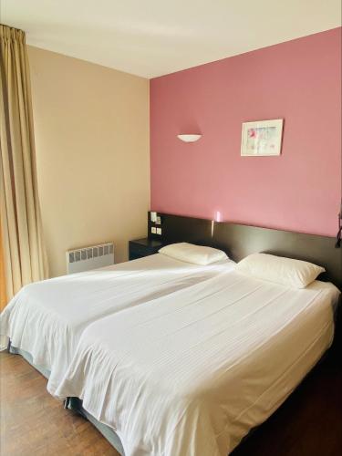 a bedroom with a large white bed with a pink wall at Résidence Le Grand Tétras- SPA THERMAL INCLUS in Ax-les-Thermes