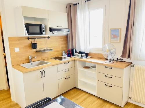 a kitchen with white cabinets and a sink and a window at LAppart de Gauche Confort en ville avec parking privé in Le Creusot