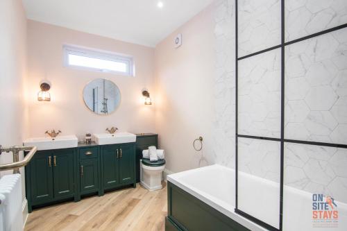 a bathroom with green cabinets and a tub and sink at OnSiteStays New Large modern 4 bed, Parking, Wifi, 2 x Bathroom in Orpington