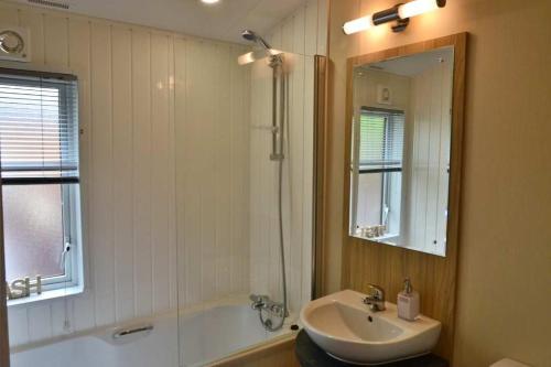 a bathroom with a sink and a tub and a mirror at Bluebell Lodge in Morpeth