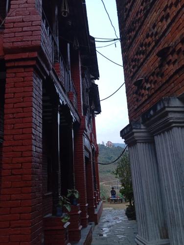 un callejón entre dos edificios de ladrillo con una persona sentada en un banco en Hotel Mountain Ridge en Bandipur