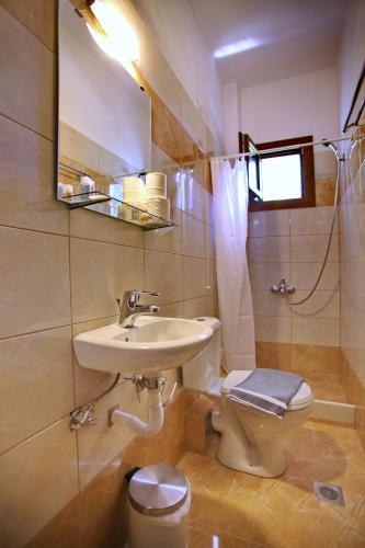 a bathroom with a sink and a toilet and a mirror at Aktaion Guest Rooms in Skopelos Town