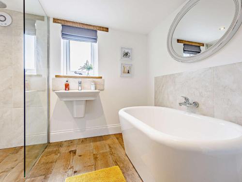 a bathroom with a tub and a sink and a mirror at 4 bed in Sidmouth 53068 in Payhembury