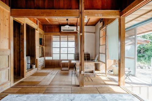 ein Wohnzimmer mit Holzböden und einem großen Fenster in der Unterkunft 【Camp House by port Side】 貸切1組の古民家/離島、美ら海への拠点 in Motobu