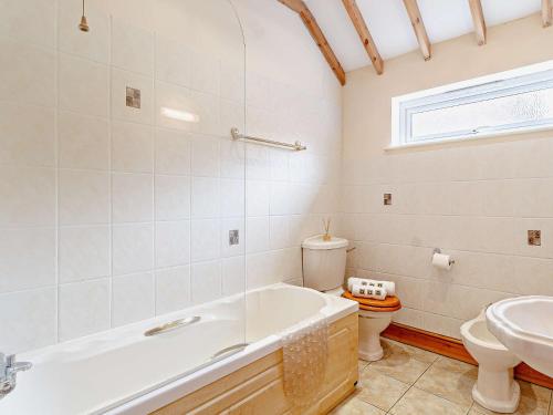 een badkamer met een bad, een toilet en een wastafel bij 2 Bed in Mattishall 57133 in Mattishall