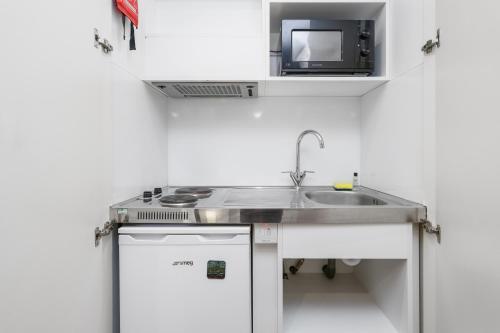 a small kitchen with a sink and a microwave at Private Studio Flat in London