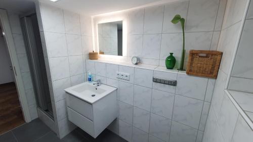 a white bathroom with a sink and a mirror at City Appartement Cologne North in Dormagen