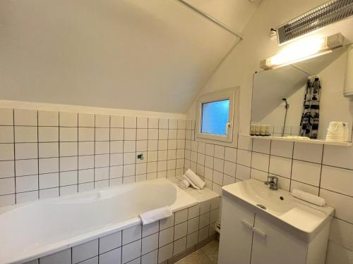 une salle de bain blanche avec une baignoire et un lavabo dans l'établissement Le Mollien, à Calais