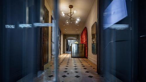 a hallway with blue walls and a chandelier at Hotel De Guise Nancy Vieille Ville in Nancy