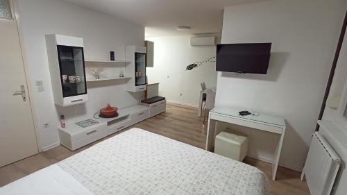 a small white room with a bed and a television at Apartma Vas in Maribor