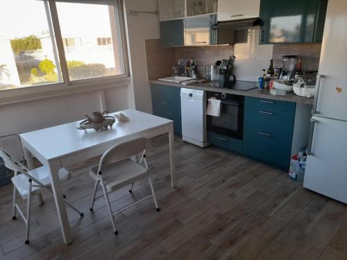 a kitchen with a white table and a white refrigerator at Les pieds dans l’eau in Baie Nettle