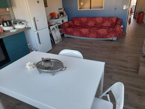 una cucina e un soggiorno con tavolo e sedie bianchi di Les pieds dans l’eau a Baie Nettle