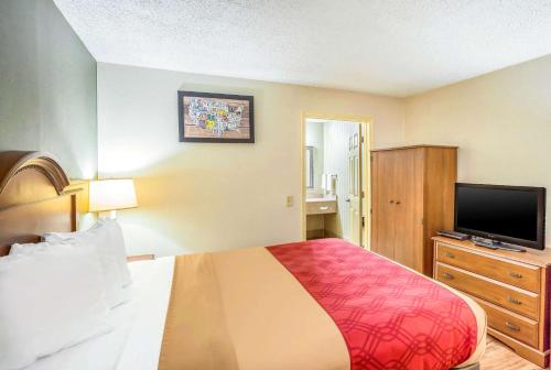 a hotel room with a bed and a flat screen tv at Econo Lodge Huntington - Barboursville University Area in Huntington