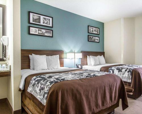 two beds in a hotel room with blue walls at Sleep Inn Scott-Lafayette West in Scott