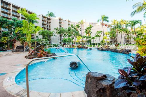 a swimming pool in a resort with palm trees at Aston Kaanapali Shores in Lahaina