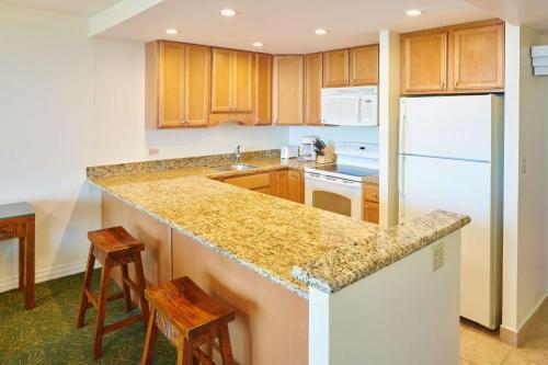 a kitchen with wooden cabinets and a counter top at Aston Kaanapali Shores in Lahaina