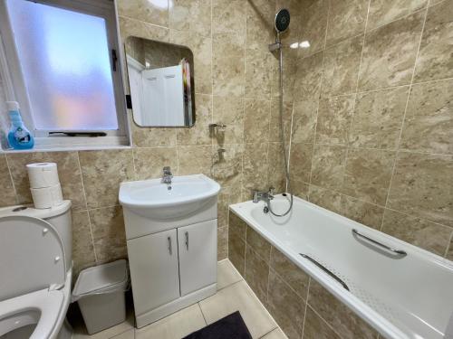 4 Bedrooms, 2 Bathrooms, Parking, Spacious House في لندن: حمام مع حوض ومرحاض وحوض استحمام
