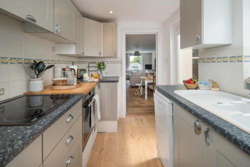 uma cozinha com armários brancos e uma bancada em Fern Cottage em Bembridge