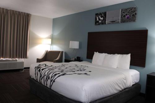 um quarto de hotel com uma cama grande e uma cadeira em Wingate by Wyndham Kings Bay Naval Base em Kingsland