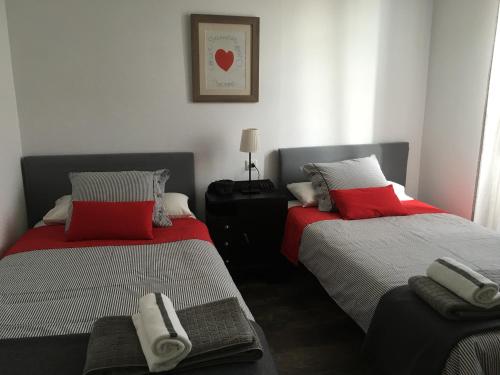 a bedroom with two beds with red and white pillows at Apartamentos cercanos playa 1 in Puentedeume
