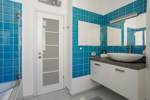 baño con lavabo y azulejos azules en Appartements BnBIsrael - Hovevei Tsiyon Jasmin, en Tel Aviv