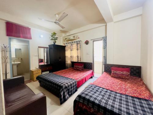 um quarto com 2 camas, uma cadeira e um espelho em Appayan Guest House Baridhara (Bhagyakula Building) em Dhaka