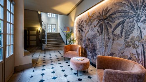 un couloir avec deux chaises et un mur orné d'une fresque murale. dans l'établissement Hotel De Guise Nancy Vieille Ville, à Nancy