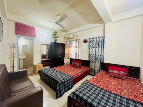 a hotel room with two beds and a chair at Appayan Guest House Baridhara (Bhagyakula Building) in Dhaka