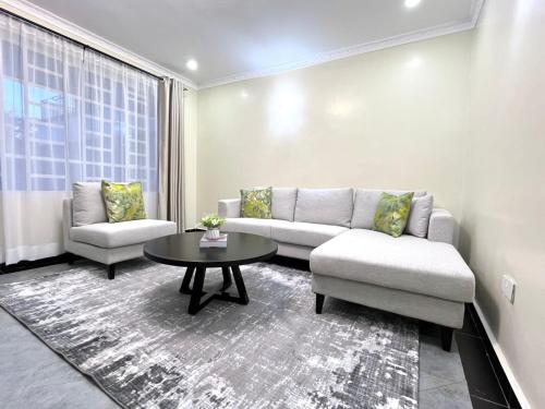 Naka Tranquil Suite with Ample Secure Parking في ناكورو: غرفة معيشة مع أريكة وطاولة