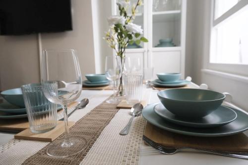 a table with plates and bowls and glasses on it at Stylish 4 Bed Home in Aylesbury, Buckinghamshire in Buckinghamshire