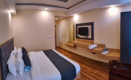 a bedroom with a large bed and a television at The Fragrance Hotel in Katra