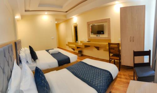 a hotel room with two beds and a desk at The Fragrance Hotel in Katra