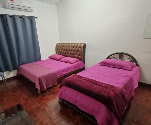 two beds in a room with purple sheets at OneB Homestay Shah Alam, 9 pax, I-city near, Wifi in Shah Alam