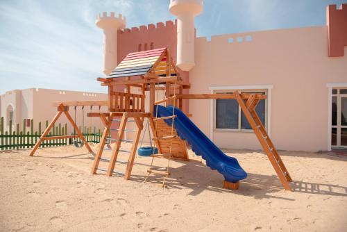 a playground in front of a house in the sand at Oyster Bay Beach Suites in Abu Dabbab