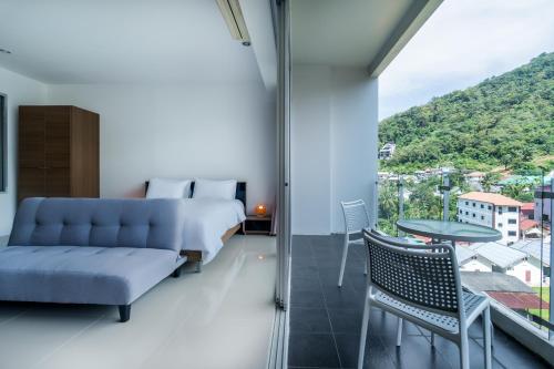 a bedroom with a bed and a couch and a window at Chic Condominium by Redfox Hospitality in Karon Beach