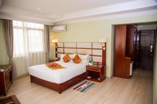 a bedroom with a large white bed and a wooden floor at Tiffany Diamond Hotels Ltd - Indira Gandhi street in Dar es Salaam