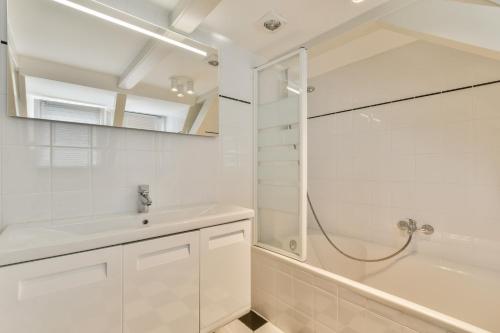 a white bathroom with a sink and a shower at Amsterdam Alley Apartment in Amsterdam