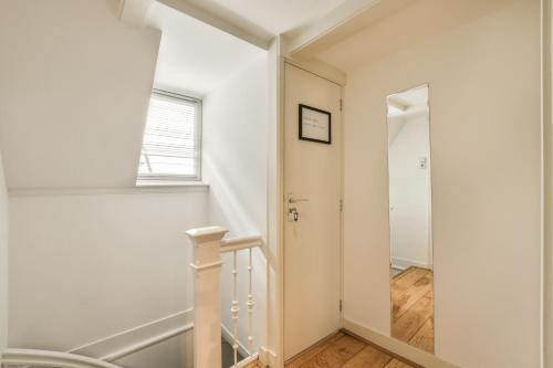a white hallway with a staircase and a mirror at Amsterdam Alley Apartment in Amsterdam