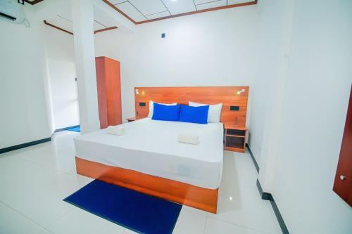 a bedroom with a large white bed with blue pillows at Central Apartment near Bentota Beach- Balcony & Kitchen in Aluthgama