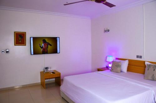 a bedroom with a bed and a tv on the wall at Roses Regency Hotel in Abuja